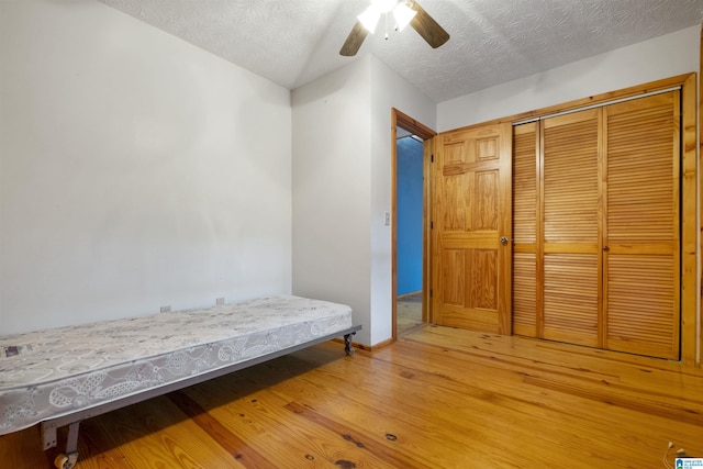 bedroom with hardwood / wood-style floors, ceiling fan, a textured ceiling, and a closet