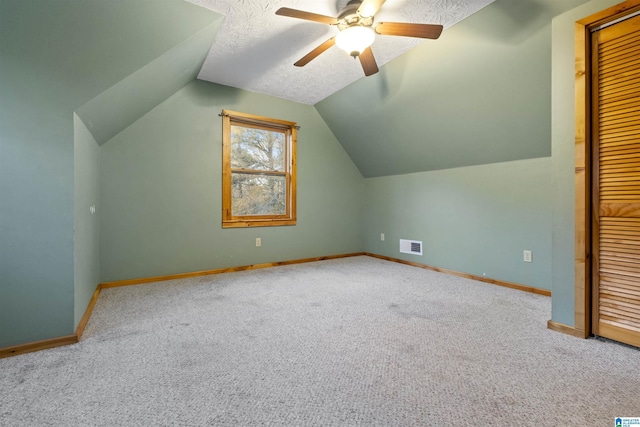 additional living space with lofted ceiling, ceiling fan, light carpet, and a textured ceiling