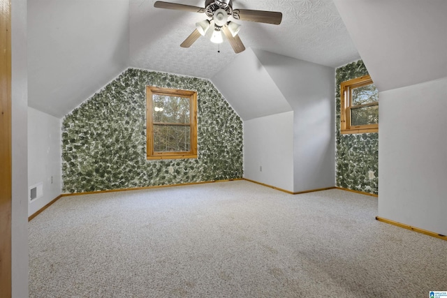 bonus room featuring a textured ceiling, vaulted ceiling, ceiling fan, and a healthy amount of sunlight