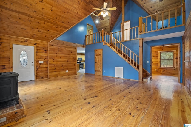 unfurnished living room with hardwood / wood-style floors, high vaulted ceiling, a wood stove, and wood ceiling