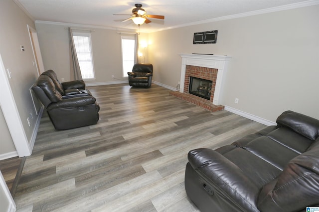 living room with hardwood / wood-style floors, a brick fireplace, ceiling fan, and crown molding