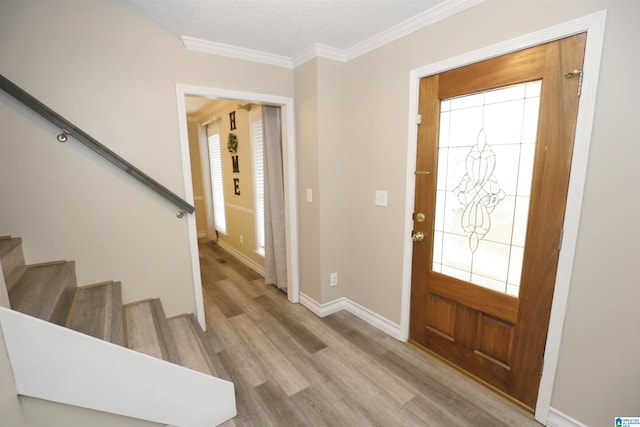 entrance foyer featuring a textured ceiling, light hardwood / wood-style floors, plenty of natural light, and ornamental molding