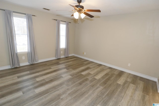 spare room featuring hardwood / wood-style floors, ceiling fan, and a wealth of natural light