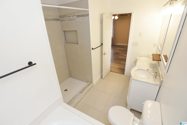 bathroom with tiled shower, hardwood / wood-style floors, vanity, and toilet