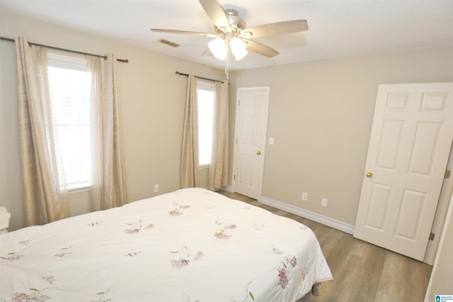 bedroom with multiple windows, ceiling fan, and wood-type flooring