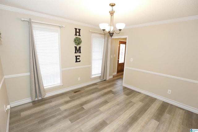 unfurnished room featuring hardwood / wood-style flooring, an inviting chandelier, and crown molding