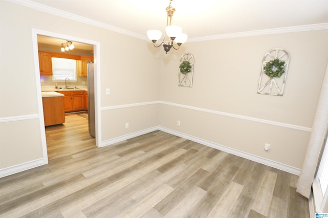 empty room featuring light hardwood / wood-style floors, crown molding, sink, and a chandelier