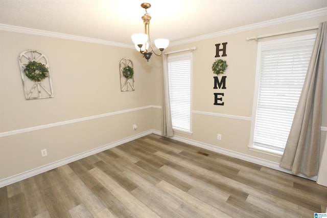 spare room featuring wood-type flooring, a notable chandelier, and ornamental molding