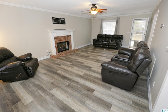 living room with hardwood / wood-style flooring, ceiling fan, ornamental molding, and a brick fireplace