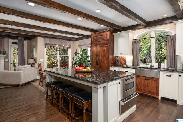 kitchen with white cabinets, dark hardwood / wood-style floors, a kitchen island, and beamed ceiling