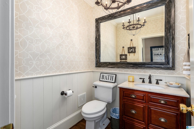 bathroom with toilet, vanity, a notable chandelier, and ornamental molding