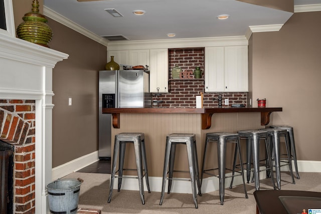 bar with white cabinetry, stainless steel fridge, crown molding, and dark carpet