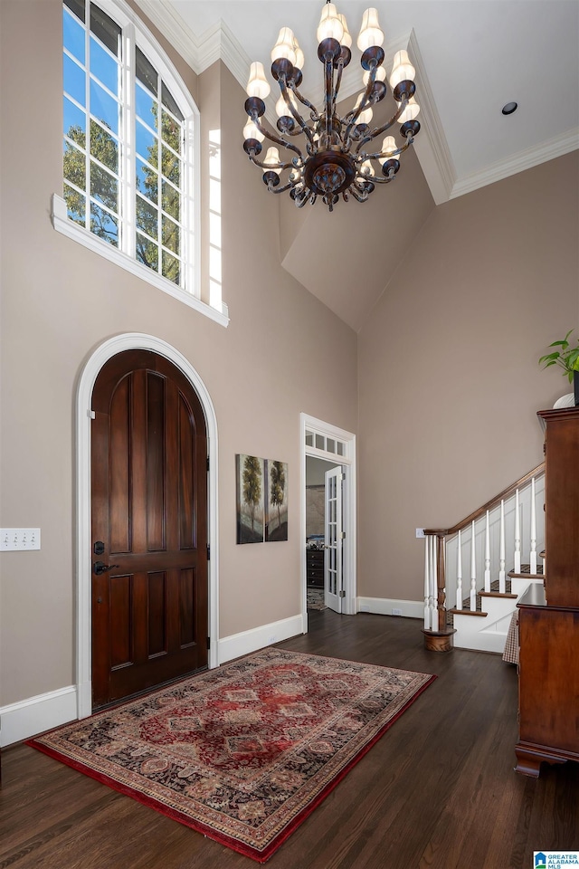 entrance foyer with dark hardwood / wood-style flooring, crown molding, and an inviting chandelier