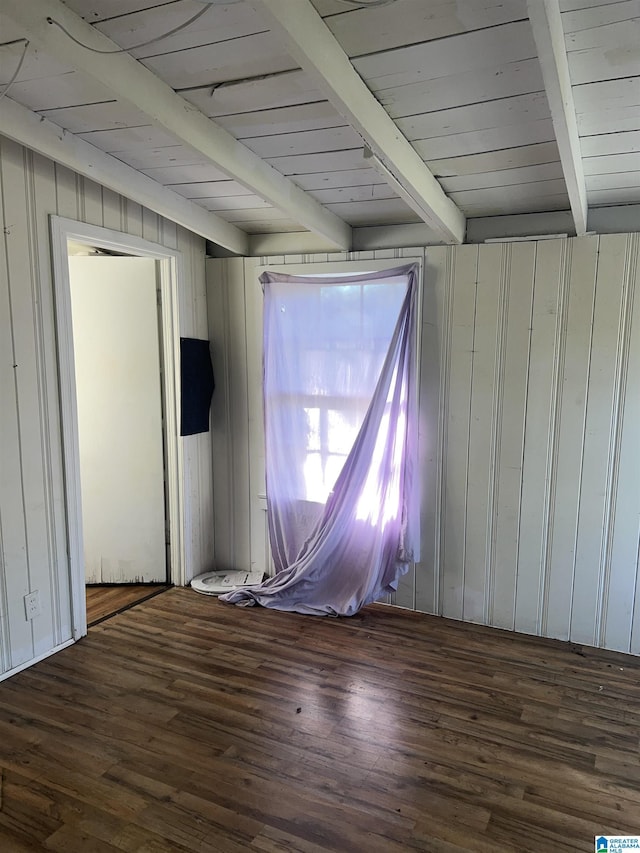 empty room featuring beamed ceiling, wood walls, dark hardwood / wood-style flooring, and wood ceiling