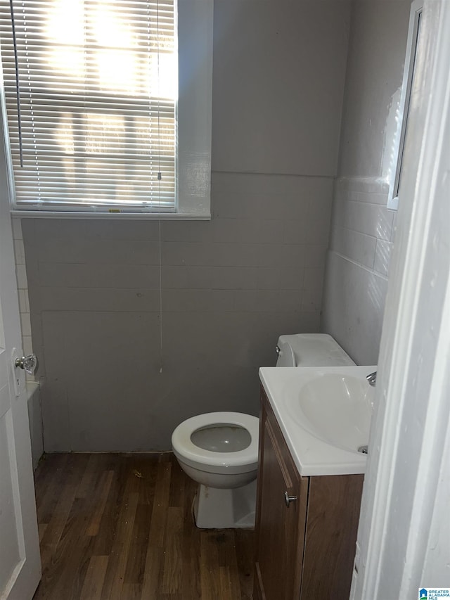 bathroom featuring hardwood / wood-style flooring, vanity, toilet, and tile walls