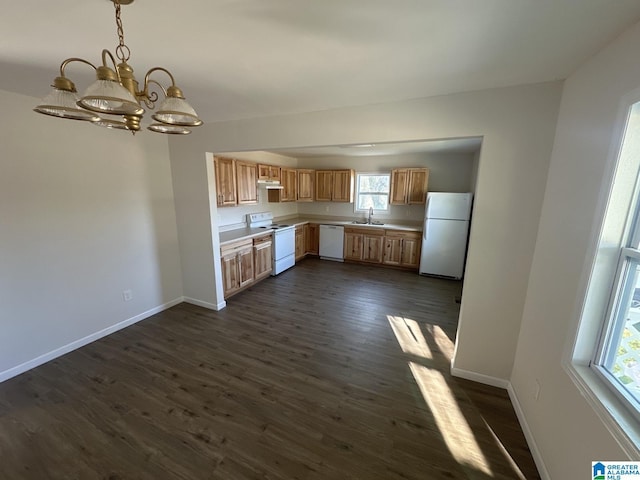 kitchen with white appliances, sink, hanging light fixtures, dark hardwood / wood-style floors, and a notable chandelier