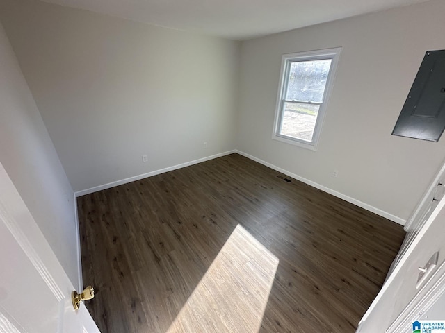 spare room featuring electric panel and dark wood-type flooring