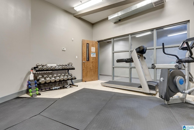 exercise room with carpet flooring and a towering ceiling