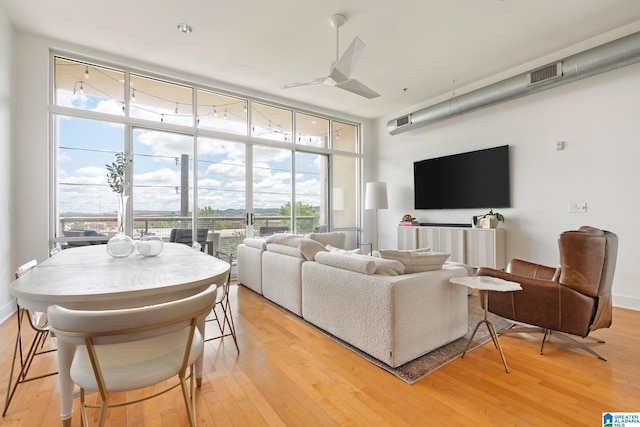 living room with a wall of windows, light hardwood / wood-style floors, plenty of natural light, and ceiling fan