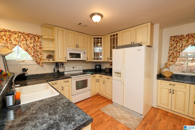 kitchen with sink, a healthy amount of sunlight, white appliances, and light wood-type flooring