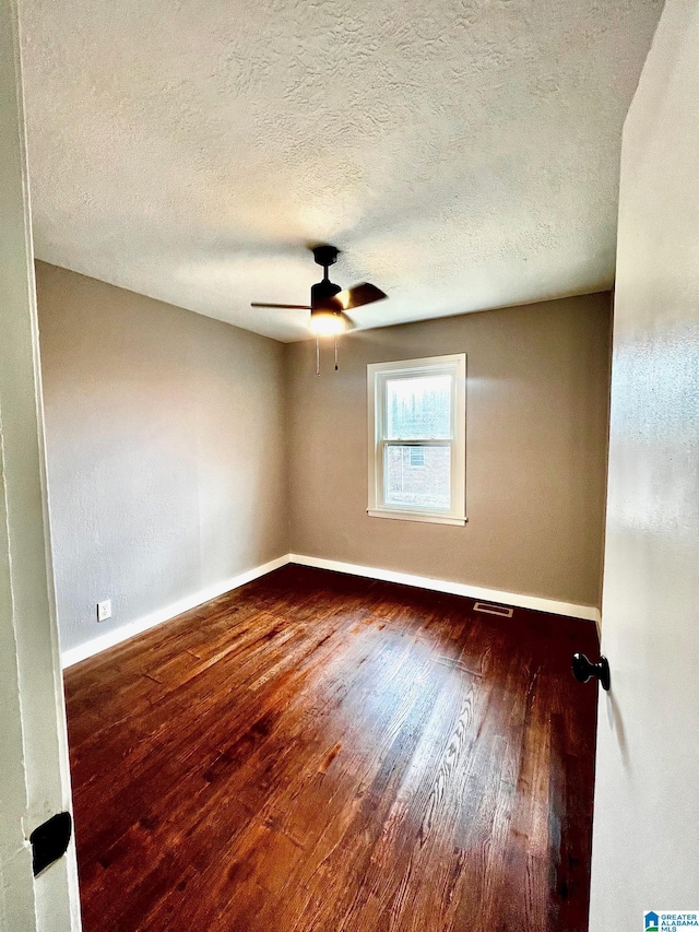 unfurnished room with ceiling fan, dark wood-type flooring, and a textured ceiling