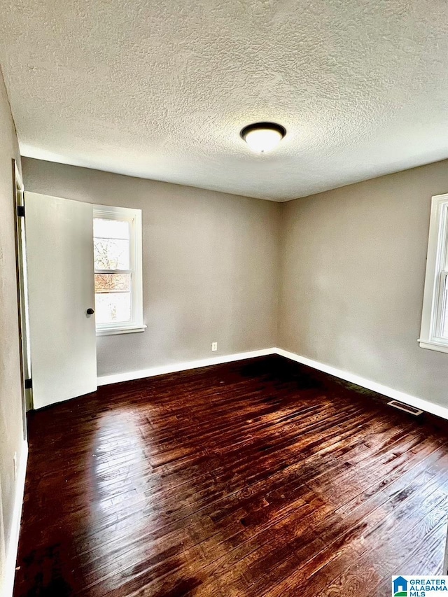 spare room with dark hardwood / wood-style flooring and a textured ceiling