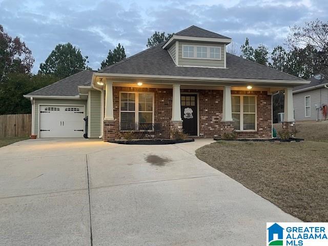 view of front of property featuring covered porch, a garage, and a front lawn