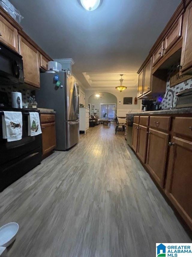 kitchen with pendant lighting, black appliances, and light wood-type flooring