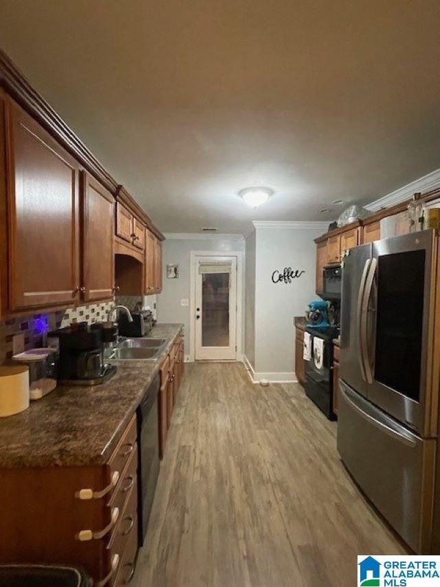 kitchen featuring light wood-type flooring, stainless steel appliances, ornamental molding, and sink