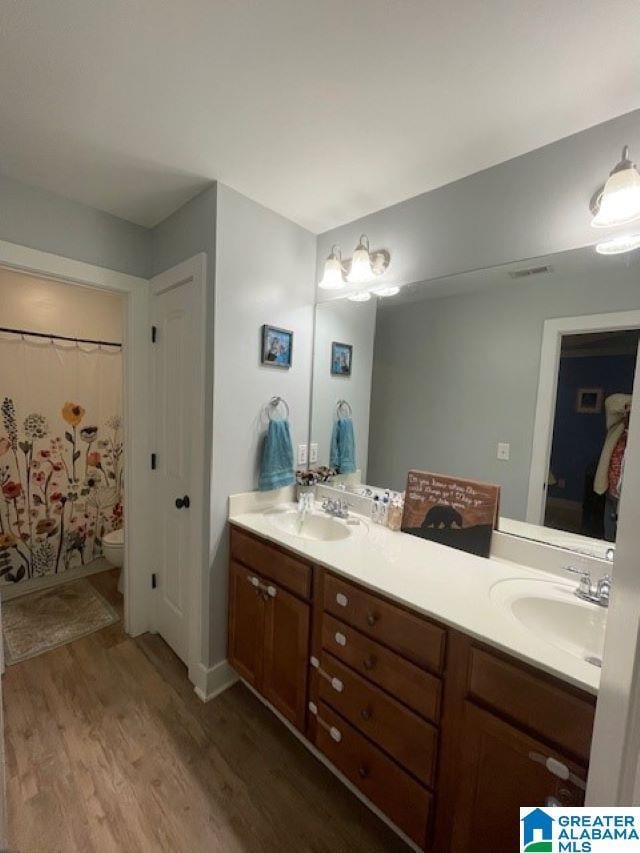 bathroom featuring a shower with shower curtain, wood-type flooring, vanity, and toilet