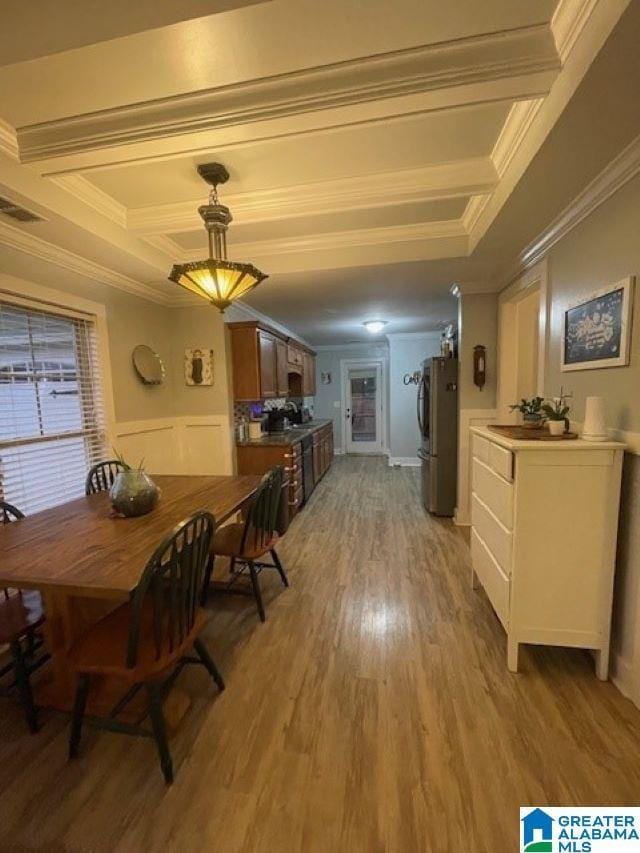 dining space with light wood-type flooring and crown molding