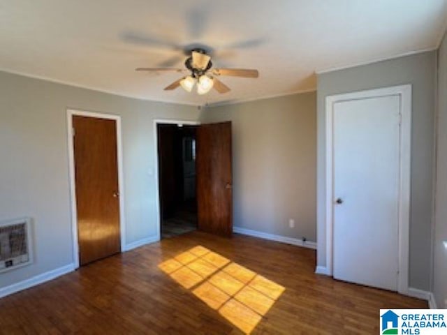 unfurnished bedroom with ceiling fan, dark hardwood / wood-style flooring, and heating unit