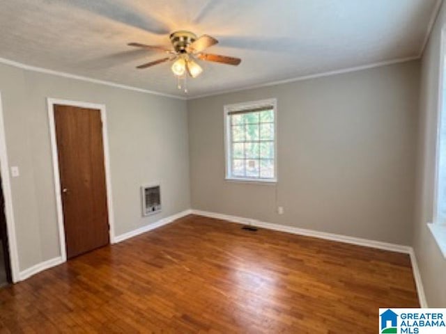 spare room with heating unit, crown molding, ceiling fan, and dark wood-type flooring