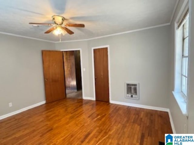 empty room featuring hardwood / wood-style floors, heating unit, ceiling fan, and ornamental molding