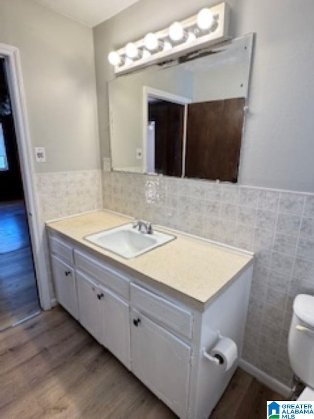 bathroom featuring vanity, wood-type flooring, tile walls, and toilet