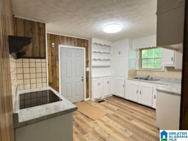 kitchen featuring white cabinets, sink, light wood-type flooring, a textured ceiling, and black electric cooktop