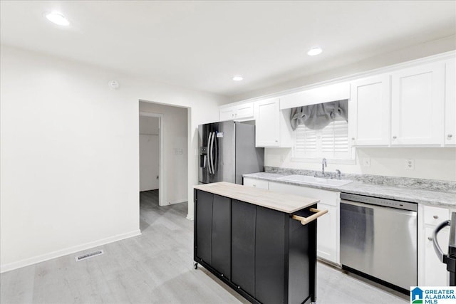 kitchen with a center island, sink, stainless steel appliances, white cabinets, and light wood-type flooring