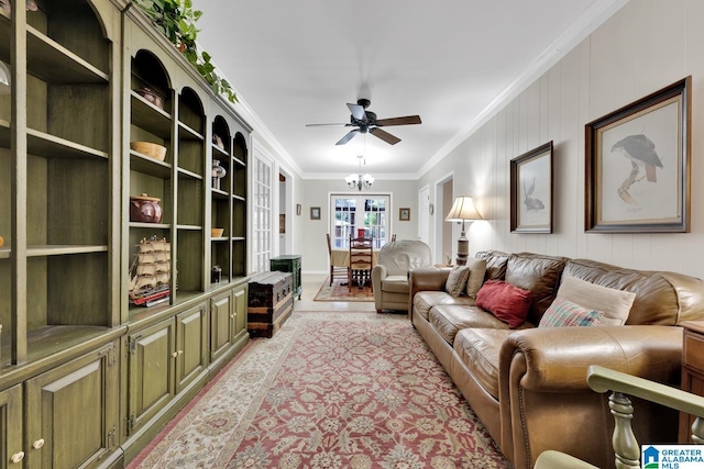 living room featuring crown molding, wooden walls, and ceiling fan with notable chandelier