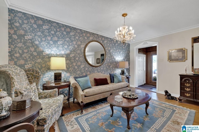 living room with crown molding, wood-type flooring, and a notable chandelier