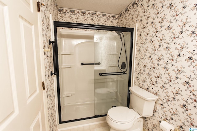 bathroom with a textured ceiling, toilet, and walk in shower