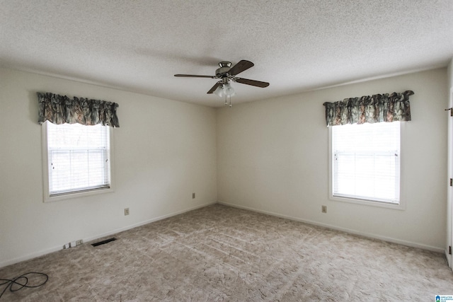 unfurnished room featuring ceiling fan, light colored carpet, and a textured ceiling