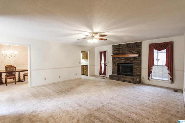 unfurnished living room featuring a fireplace, light colored carpet, a textured ceiling, and ceiling fan with notable chandelier