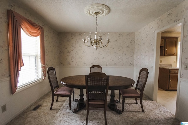 carpeted dining room with a textured ceiling and an inviting chandelier