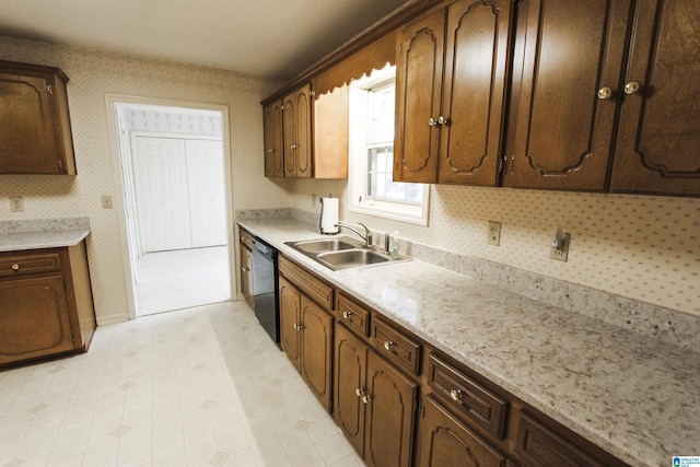 kitchen with dark brown cabinetry, light stone countertops, dishwasher, and sink