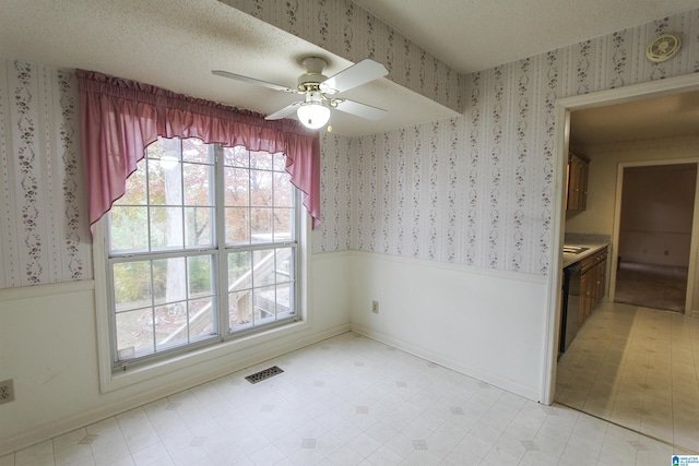 unfurnished dining area with a textured ceiling and ceiling fan