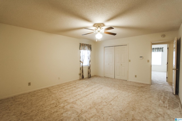 unfurnished bedroom with carpet, ceiling fan, a textured ceiling, and a closet