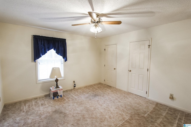 unfurnished bedroom featuring multiple closets, ceiling fan, light carpet, and a textured ceiling