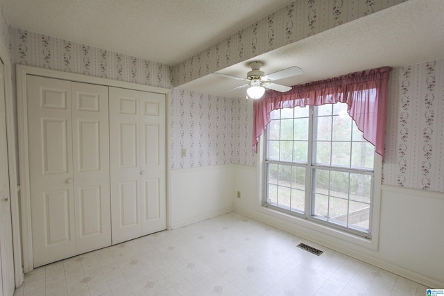 unfurnished bedroom with ceiling fan, a textured ceiling, and a closet