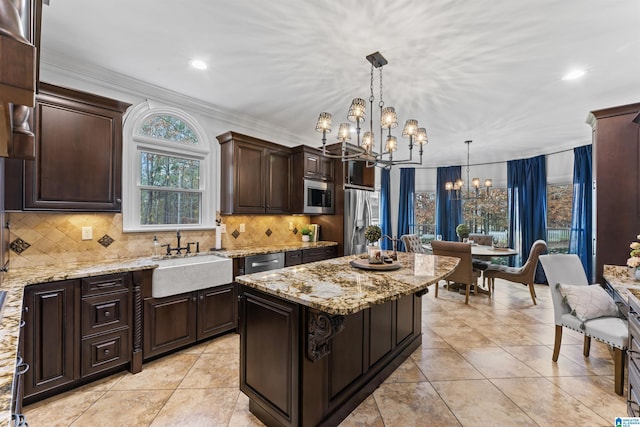 kitchen featuring appliances with stainless steel finishes, sink, pendant lighting, an inviting chandelier, and a kitchen island