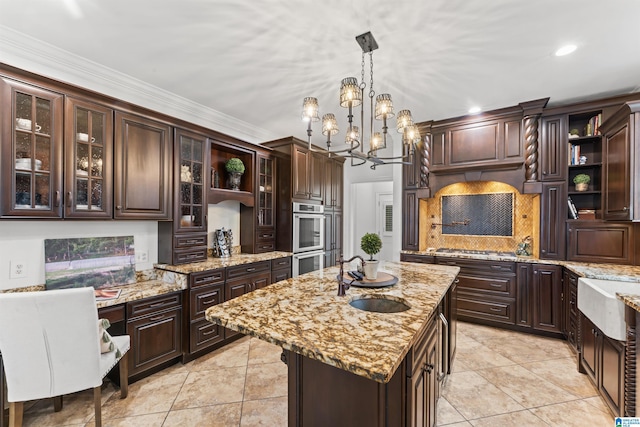 kitchen featuring hanging light fixtures, ornamental molding, an island with sink, dark brown cabinets, and stainless steel appliances